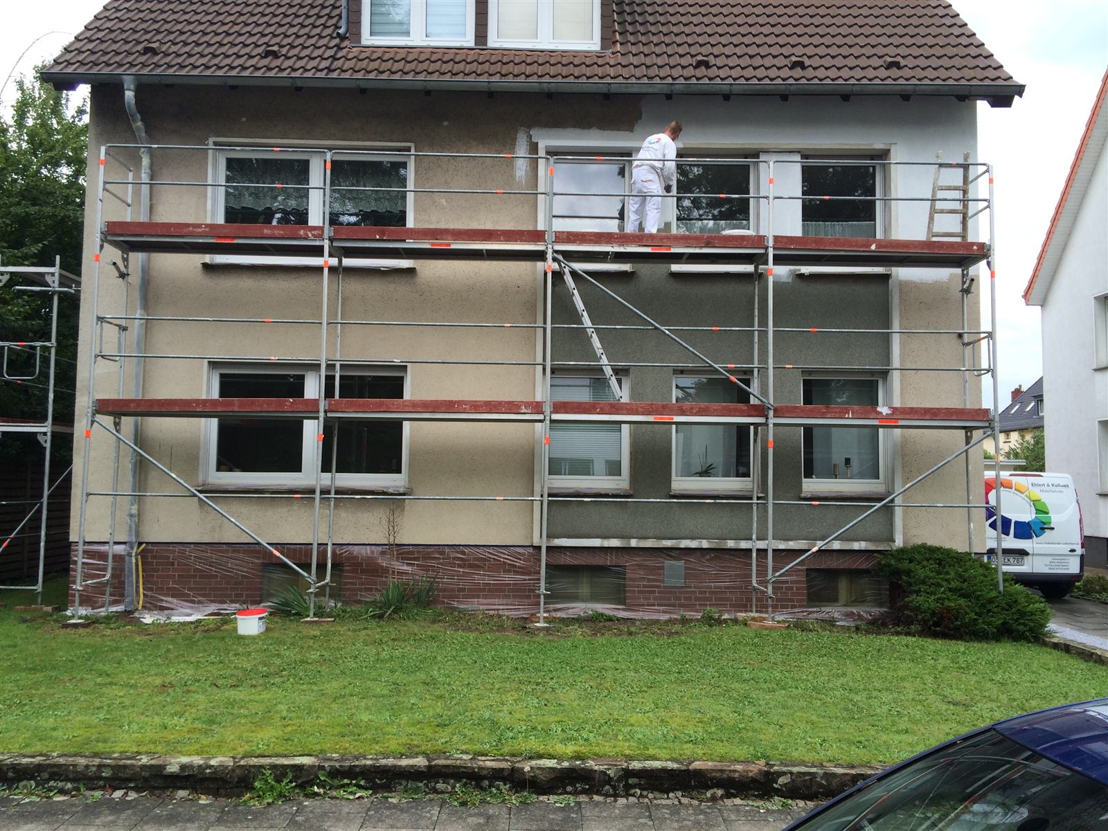 Maler bei Fassadenarbeiten auf dem Gerüst