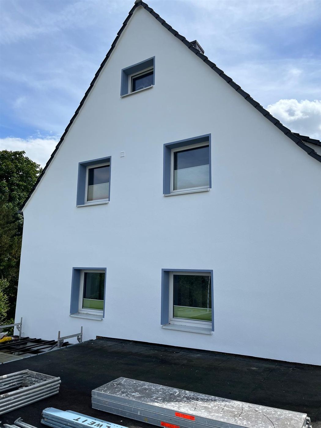 Frisch gestrichene weiße Giebelfassade mit farblich abgesetzten Fensterlaibungen
