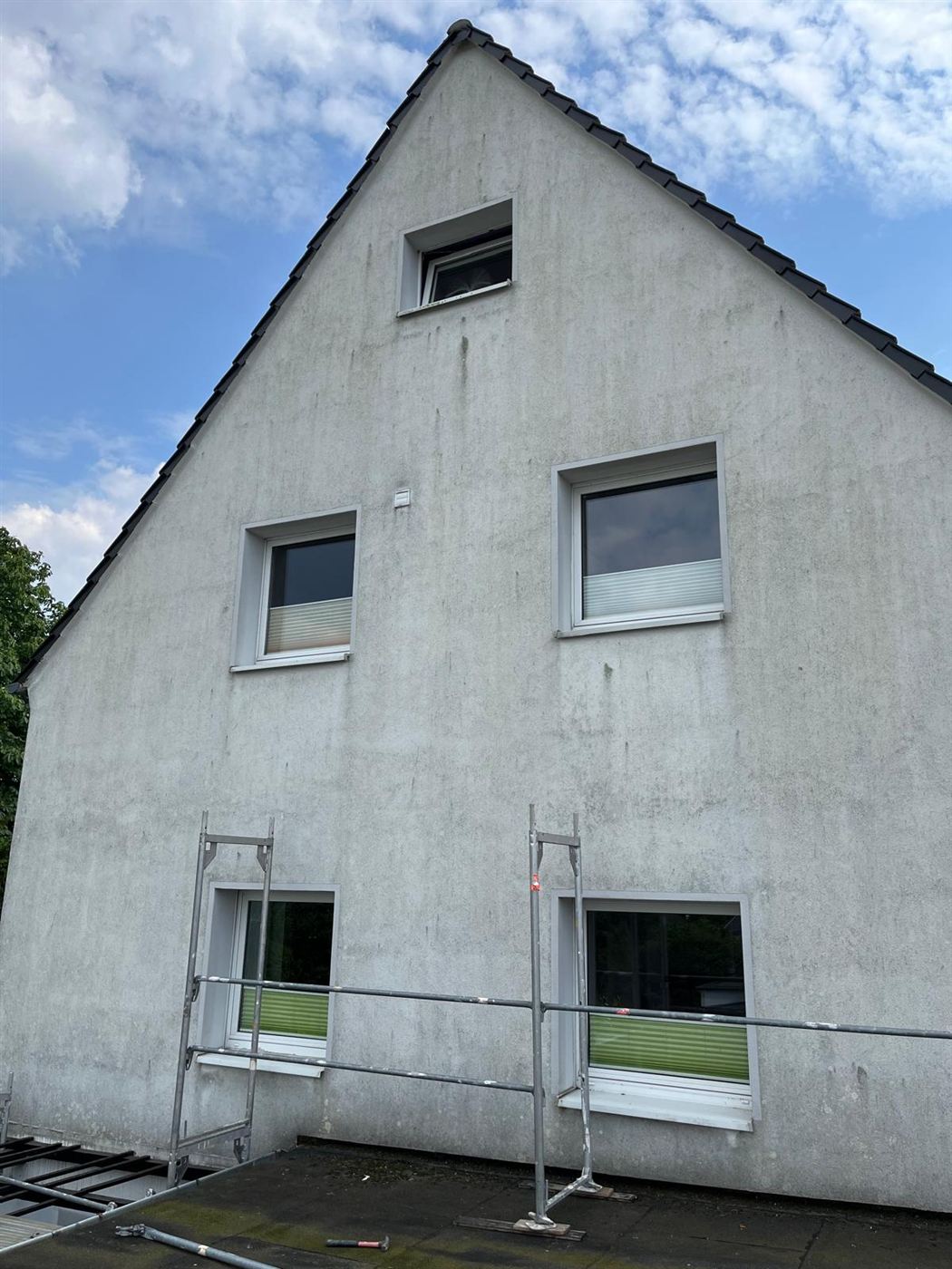 Verwitterte, vergraute Giebelfassade vor der Sanierung